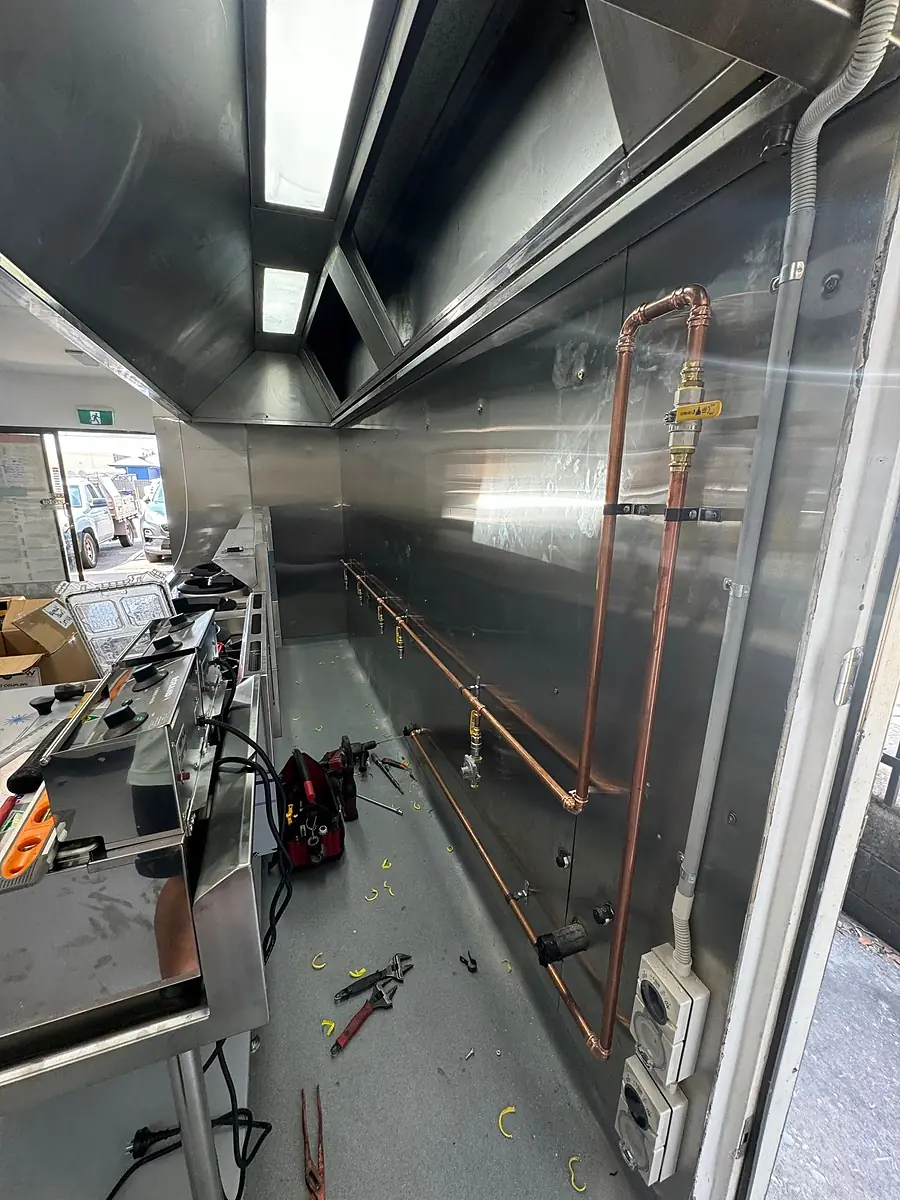 Copper gas line and valves installed in a commercial kitchen under the extraction canopy