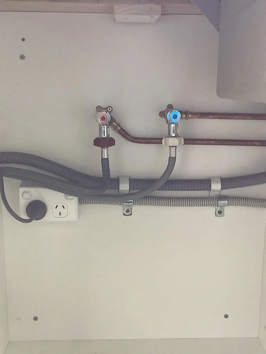 Copper and flexible pipework rough-in with hot and cold isolation taps under a bench